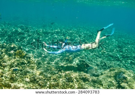Woman with mask snorkeling in clear water