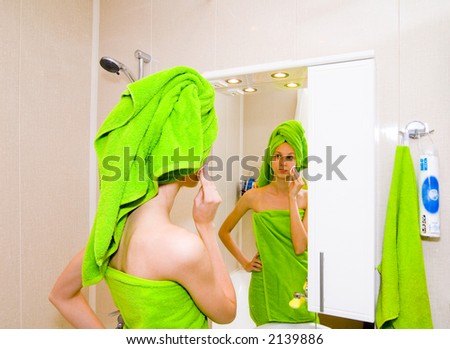 Girl covered in green towel looking in mirror
