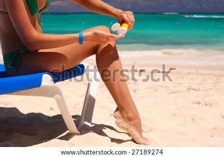 Tan woman applying sun protection lotion