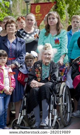 NOVOANNINSKY, RUSSIA - MAY 09: Female World War II veteran sitting in wheelchair with a bouquet of flowers on the Victory Day celebration on May 9, 2015 in Novoanninsky, Volga region, Russia