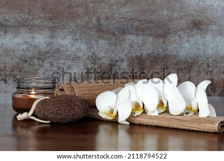 Spa composition with candles, towel, orchid and pumice stone against a brown background. Stock fotó © 