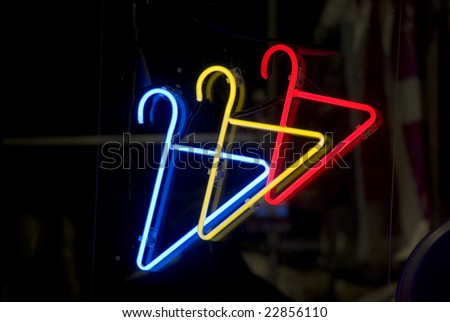Neon sign showing hangers in the window of a Harlem, New York City dry cleaning store