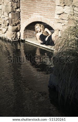 gothic young woman lying by the lake facing the camera