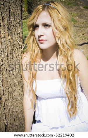 angelic portrait of young girl leaning on a tree