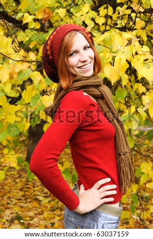 young redhead girl in warm autumn dress standing and smiling outdoor, side view