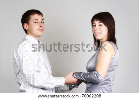 man and woman in evening dress holding for hands, smiling and looking at camera