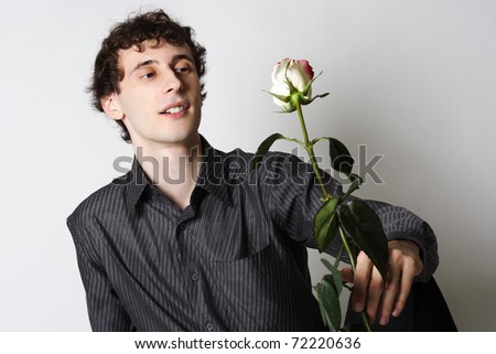 man in black shirt sitting, holding rose and looking on it