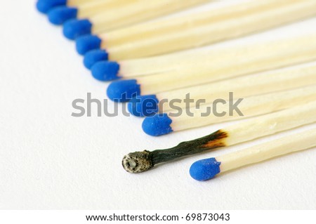 Macro closeup of a group of matches, one match burned, isolated on white background