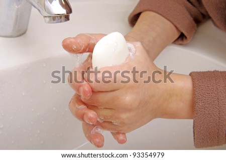 Boy washes with running water and soap hands