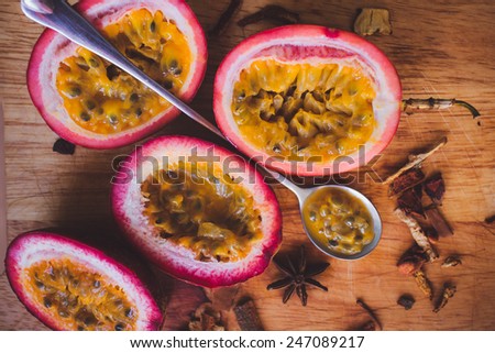 Close up yellow color passion fruit (maracuya) pulp and seed in small ceramic bowl isolated on BROWN board, spoon, spices