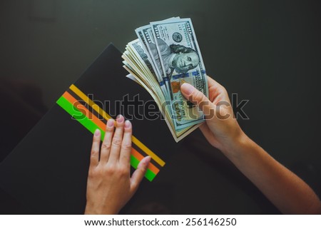 Money in human hands, women giving a lot of 100 dollars, with business folders , on a black background