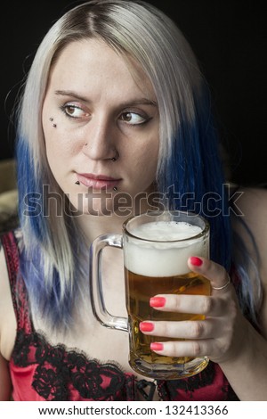 Portrait of a beautiful young woman with blue hair drinking a mug of beer.