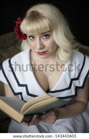 Portrait of a beautiful young woman with blond hair and brown eyes reading an antique book.