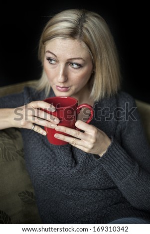 Portrait of a blonde woman with blue eyes holding a red coffee cup.
