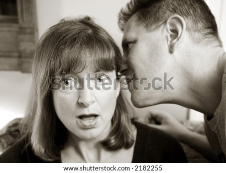 Photo of an attractive man telling a woman a surprising secret.