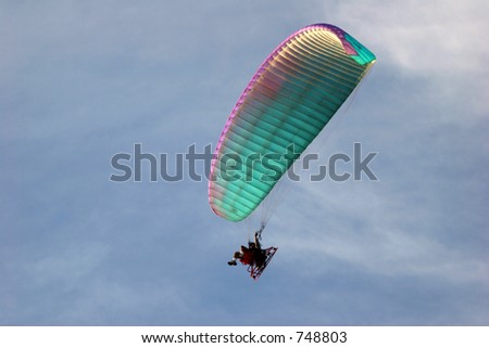 Para glider with a propeller on his back soaring the blue sky.