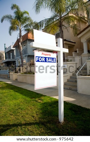 White, red and blue property for sale sign in front of the suburban house. There is some additional space for text on the sign.