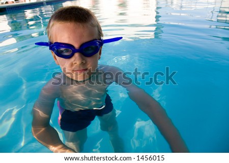 Young boy wearing diving mask or goggles in the swimming pool afternoon.