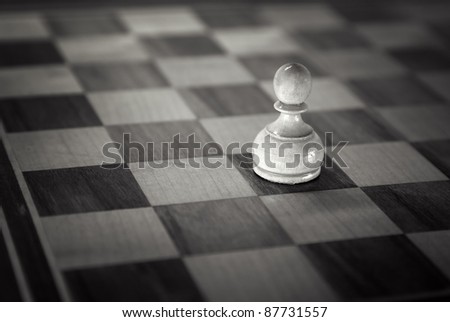 White pawn down on the chessboard . Black and white retro toned photo with shallow DOF and space for your text