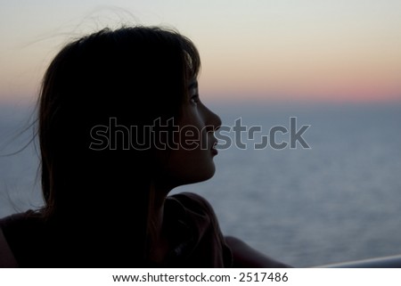 young girl on a cruise looking off into the distance at sunset