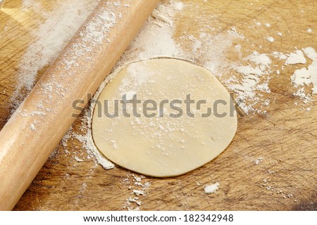 Wooden rolling pin with remnants of flour and stretched dough