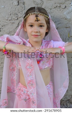 Little Eastern Beauty; a little girl in Eastern-styled fancy costume against a roughly plastered wall