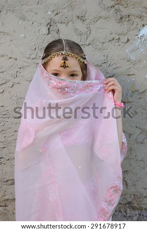 Little Eastern Beauty; a little girl in Eastern-styled fancy costume against a roughly plastered wall
