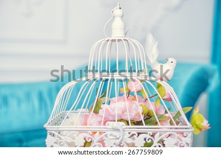 White cage with flowers and bird as decoration on wedding.