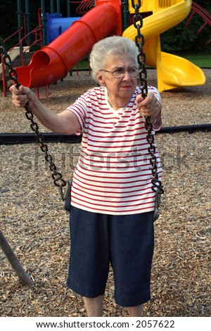 Senior citizen woman on a playground swing.