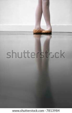 Young dancer in 5th position.. low angle shot of just feet and legs - this view has had the color removed from the floor and wall.