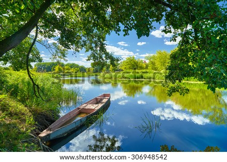 Spring summer landscape blue sky clouds Narew river boat green trees countryside grass Poland water leaves