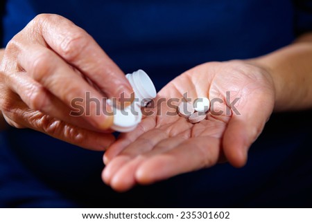 Hands of elderly female with pills. Pharmaceutical background
