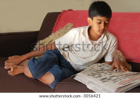 a young asian boy reading newspaper