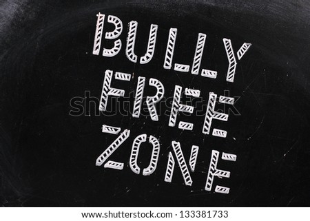 The words Bully Free Zone in chalk stencil letters on a well used blackboard, which might be used for a campaign to stop bullying at school or work