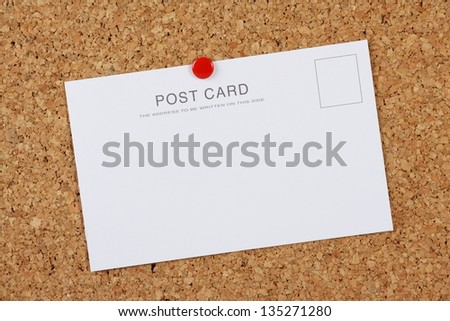 A blank, white postcard with copy space pinned to a cork notice board using a red drawing pin