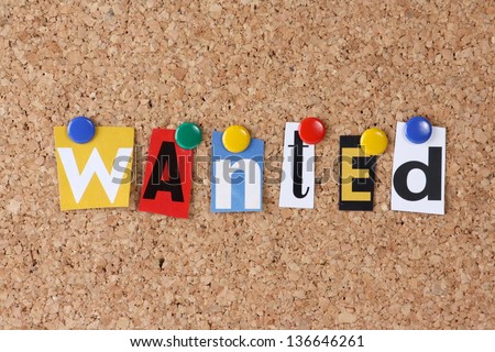 The word Wanted in cut out magazine letters pinned to a cork notice board