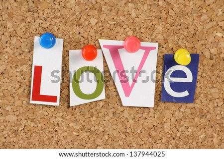 The word Love in cut out magazine letters pinned to a cork notice board