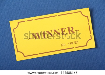 Winning Golden or yellow raffle or lottery ticket on a blue woven material background