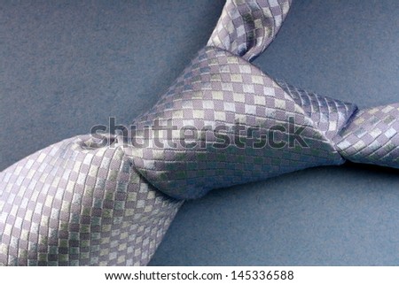 Close up of a purple neck tie which has been tied in a knot and placed on a background of purple paper. A neck tie is as an essential part of your presentation in business meetings and interviews.