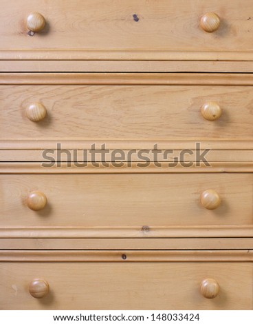 Close up of a used chest of drawers made from pine wood and treated with a wax coating.