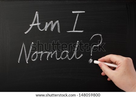 Hand writing the words Am I Normal on a blackboard. A question people ask themselves in times of anxiety,confusion and self doubt which can lead to therapy and a new self awareness.