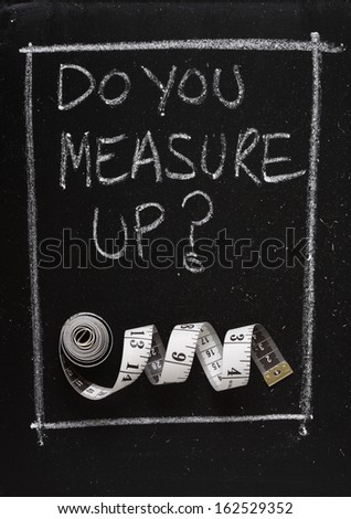 Do You Measure Up? written on a blackboard next to a measuring tape. A phrase used to question if you are up to the task or job, or to suggest that size does matter.