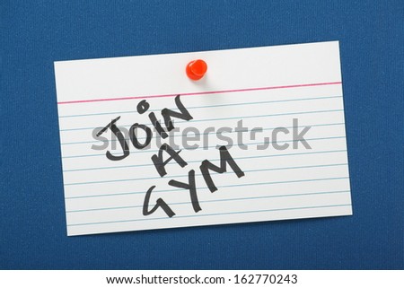 A reminder to Join A Gym written on a white note card pinned to a blue notice board