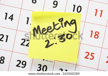 Meeting Reminder written on yellow paper sticky note and stuck to a wall calendar