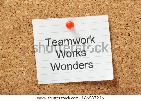 The phrase Teamwork Works Wonders typed on a piece of lined paper and pinned to a cork notice board