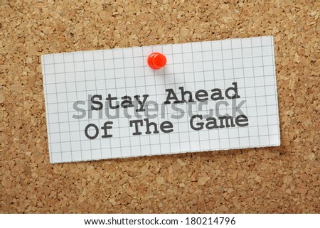 Stay Ahead of the Game typed on a piece of graph paper and pinned to a cork notice board. In business this means staying ahead of your competitors and working to anticipate market forces.