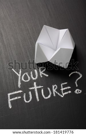 Origami Fortune Teller made from white paper on a blackboard next to the question Your Future? written by hand in chalk