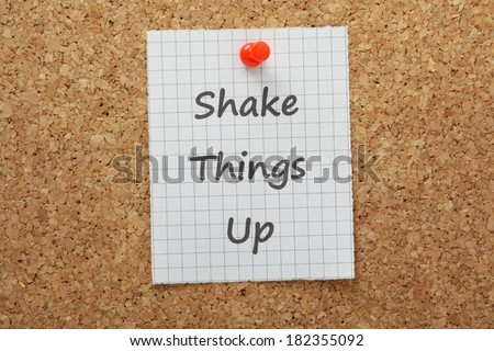 The phrase Shake Things Up on a piece of graph paper pinned to a cork notice board. A concept for making radical changes in business or in your personal life
