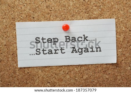 The phrase Step Back and Start Again typed on a paper note and pinned to a cork notice board. Sometimes in business and in life we have to take a step back and change direction.