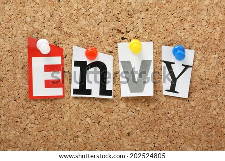 The word Envy, one of the seven deadly sins in cut out magazine letters pinned to a cork notice board